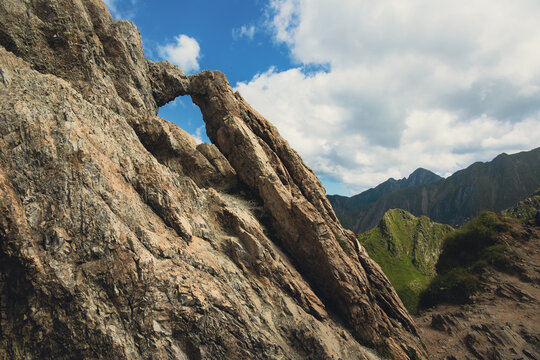 Natural rock arch window against blue sky on a mountain ridge