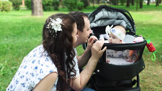 Mother and father gently push baby stroller. Baby rests peacefully in car seat. Pedestrian cross is visible nearby. Scene portrays calm, everyday parenting moment