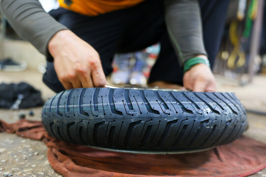 Tire inspection automotive repair mechanic hand tread rubber wheel garage close view of new tire check during maintenance with careful grip on textured surface