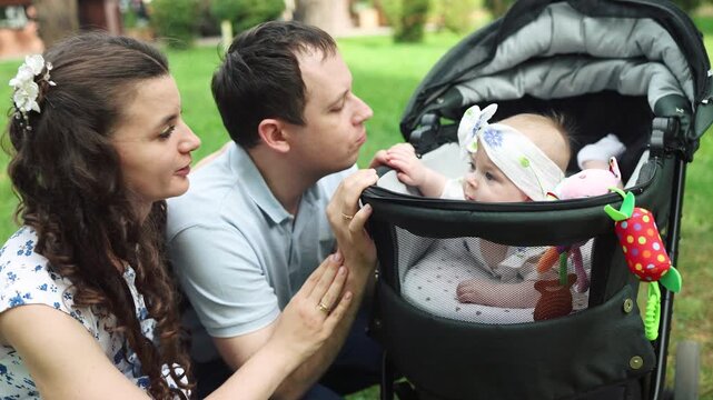 Mother and father gently push baby stroller. Baby rests peacefully in car seat. Pedestrian cross is visible nearby. Scene portrays calm, everyday parenting moment