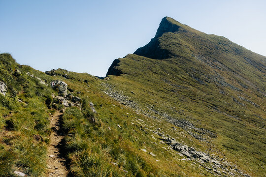 Steep green grassy ridge ascending towards the mountain summit