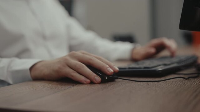Close-up of man working on computer experiencing sudden wrist pain, stops typing, gestures in discomfort, massages sore joint. Concept of RSI and carpal tunnel syndrome from office work, slow motion.
