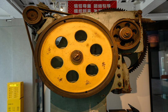 Old Industrial Machinery with Large Yellow Flywheel in Workshop