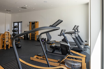 Fototapeta premium Modern hotel gym room with treadmill cardio machines and rowing rower