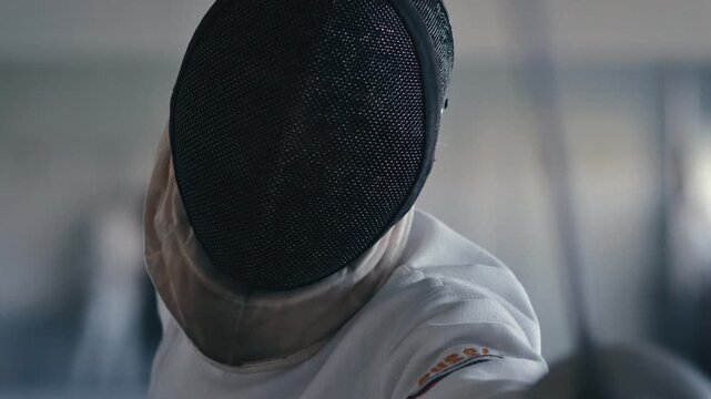 Fencing sport. Sportsmen fencing training. Two swordsmen are doing sword moves. Fencer players in gym, indoor sports club. Two athletes practice epee, uniforms and masks. Olympic combat sport.