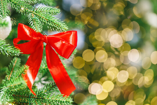 Red bow on Christmas tree with festive golden lights