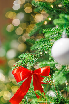 Red bow on Christmas tree with festive golden lights