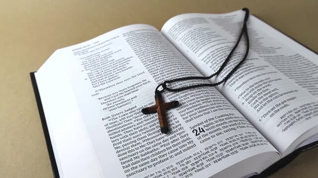 Close up view of a christian wooden cross resting on the open pages of the Holy Bible, symbolizing faith, devotion, and religious study with the sacred text and religious scripture
