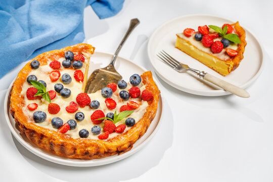 Whole berry tart with missing slice on white background