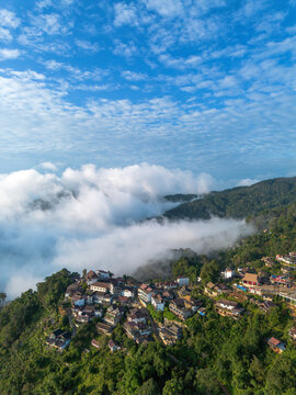 Aerial landscape view mountain village cloud mist blue sky above forest hill create peaceful travel scenery with rural house, green valley, soft fog, calm nature horizon