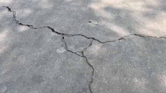 Intersecting cracks pattern on grey concrete pavement texture