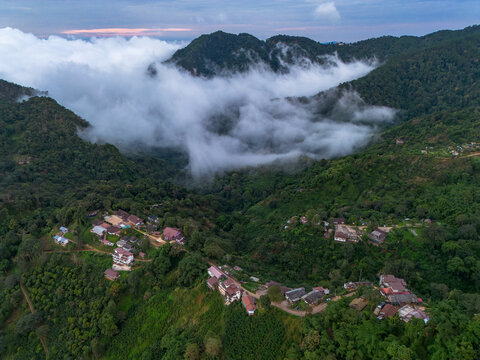 Aerial mountain village cloud forest northern thailand mist rural landscape at dawn, green hill, dense tree, valley, house, road, peaceful highland scenery