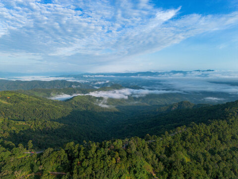 Aerial mountain landscape forest ridge cloud blue sky mist valley, aerial mountain landscape with forest ridge, drifting cloud, misty valley, and bright blue sky over green wilderness panorama