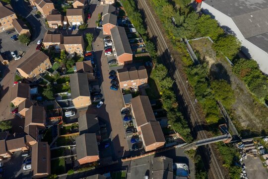 Top down aerial view of a Castleford residential estate in Yorkshire beside railway tracks showing rows of brick houses parked cars gardens roads trees and a pedestrian footbridge