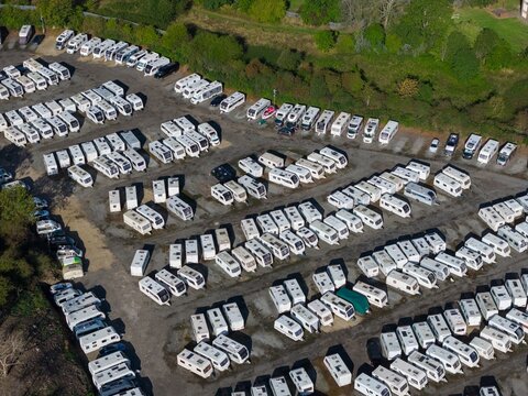 Aerial view of a large caravan storage yard in Castleford Yorkshire showing rows of white touring caravans and motorhomes parked on open ground beside trees and nearby green space