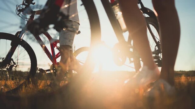 People riding bikes in nature, closeup view of wheels, happy family weekend. Woman and boy rolling bikes on lawn, rural life, bicycle trip in summer vacation, enjoy holidays, slow motion, details