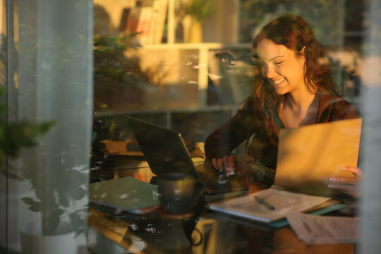 Happy telecommuter holding folder checking laptop at sunset