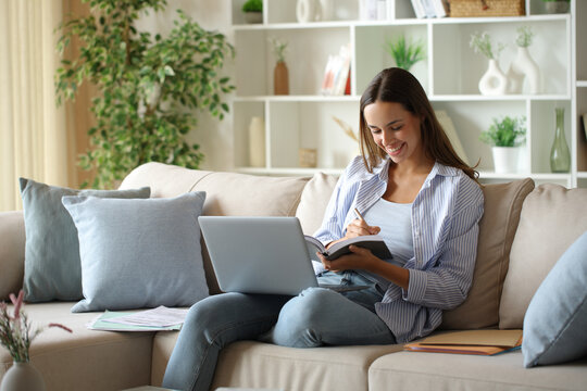 Happy telecommuter writing notes in paper agenda working at home