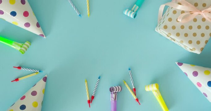 Birthday flat lay with a party hat, festive candles, a gift and place for text on a blue background. 4K Stop motion animation