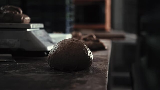 Male hands shaping bread dough ball on dark wooden counter top, baker preparing loaves for baking professional kitchen of small bakery. Close up view