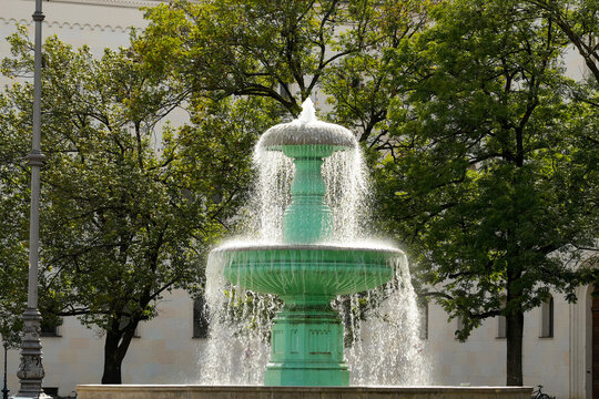 Historic bowl fountain on Geschwister-Scholl-Platz in front of the LMU main building in Munich. Neoclassical twin fountain with flowing water.