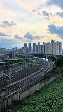 Vertical Video: High-speed train weaving through layers of city buildings under a warm sunset