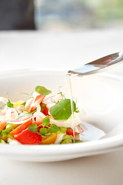 Gourmet summer salad with tomatoes, strawberries, and fresh herbs in a white bowl. Fine dining restaurant dish isolated on white background