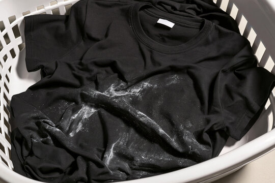 Black t-shirt with chalk marks in a white laundry basket  