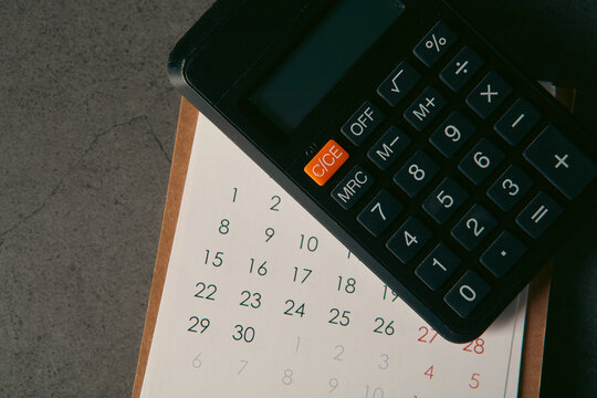 Calendar with calculator on black table, business and finance concept.