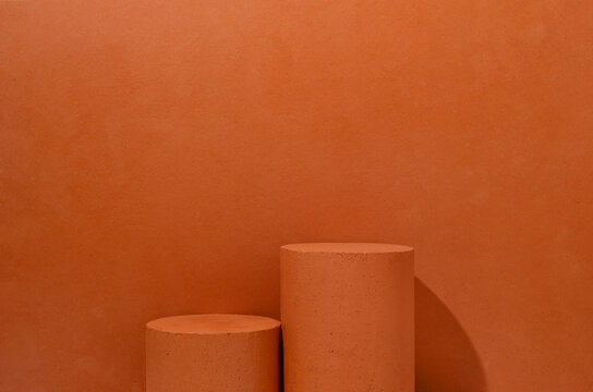 Two terracotta textured cylinder product display podiums of different heights placed in a terracotta scene, providing a clean product staging setup with open copy space.
