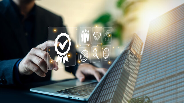 Businessman pointing at virtual quality assurance badge and business management icons on screen with building overlay. Concept of quality control, standard certification, and service excellence.