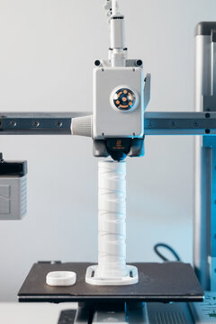 3D printer head printing a detailed white plastic component