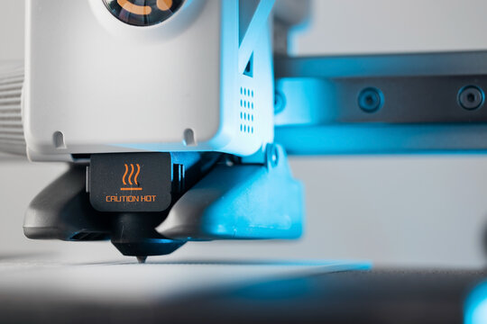 Close up of 3D printer nozzle with caution hot warning sign