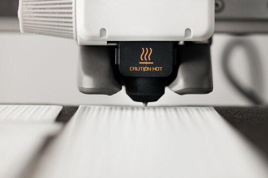 Close up of 3D printer nozzle with caution hot warning sign