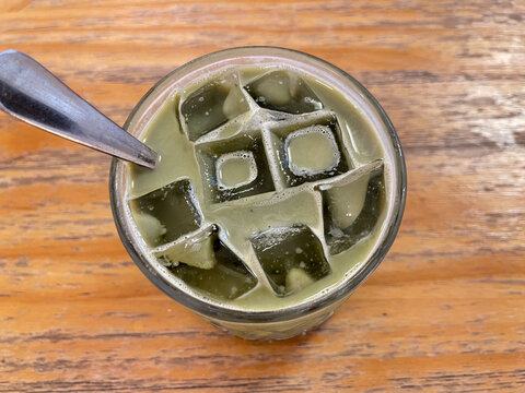 Refreshing iced matcha green tea served in a glass with ice cubes and creamy foam, popular Japanese-inspired beverage concept.