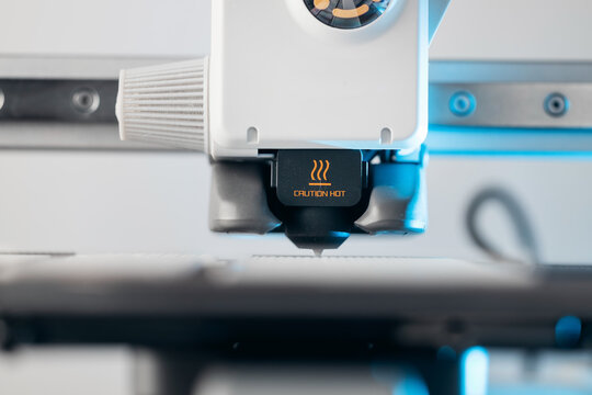 Close up of 3D printer nozzle with caution hot warning sign
