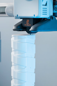 3D printer head printing a detailed white plastic component