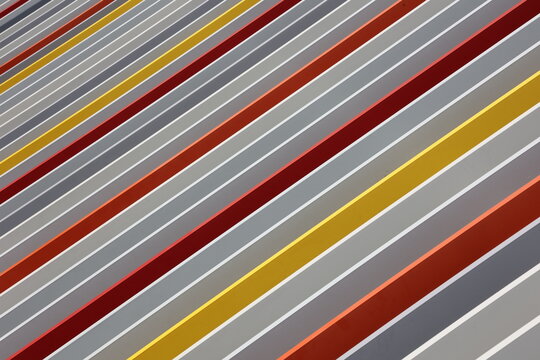 Vue rapproch&eacute;e de barres en aciers multicolores dispos&eacute;es en parall&egrave;le et formant un ensemble g&eacute;om&eacute;trique homog&egrave;ne. El&eacute;ments m&eacute;talliques peints et formant une grille de protection d&eacute;corative. 