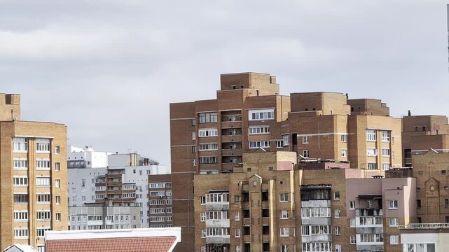 Urban landscape of residential buildings with brick facades under overcast sky, depicting modern city life and dense housing architecture with many windows.