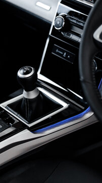 Black manual transmission gear shifter of a modern car interior, featuring a blue ambient LED light strip along the edge of the console