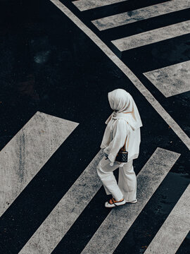 Aerial View of Woman in White Hijab Outfit Walking Across Crosswalk with Quilted Bag