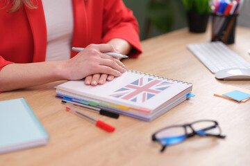 Well-prepared English teacher sits at desk with British-themed notebook. Knowledgeable language teacher prepared for conducting lesson © H_Ko