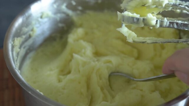 Mashed potatoes. A woman checks the doneness of mixer-whipped mashed potatoes with a spoon. Close-up.