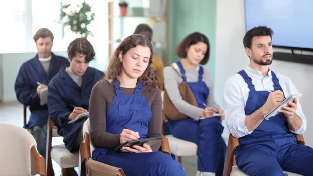 Multinational group of men and women workers listens to lecture and takes notes in lecture hall 