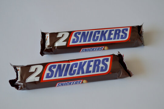 Two wrapped Snickers chocolate candy bar packages with bold brown and red branding placed flat on a clean light gray background
