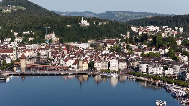 Historic Lucerne waterfront viewed from above, featuring the Chapel Bridge, Wasserturm, Reuss River and colorful old town buildings beside the calm lake.