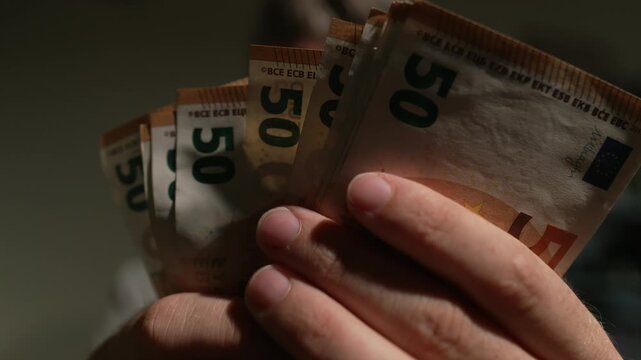 A closeup shot of male hands fanning out and counting a stack of 50 euro notes. Ideal for financial, banking, and wealthrelated content.