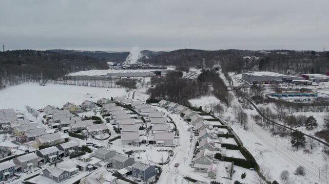 Aerial view of snowy residential neighborhood and landscape in winter, overcast sky