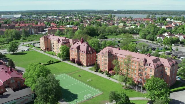 Aerial view of historic school buildings and sports field in green suburban Vanersborg
