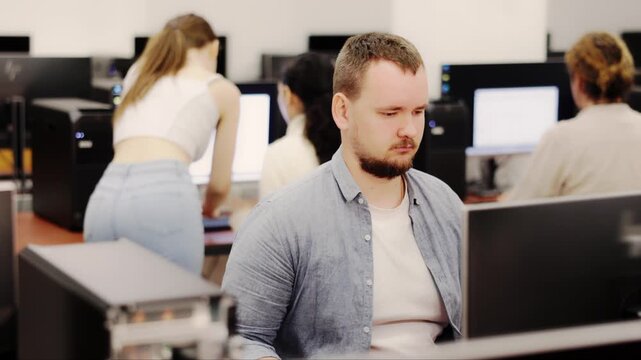 Adult man using computer for work in coworking space with team 